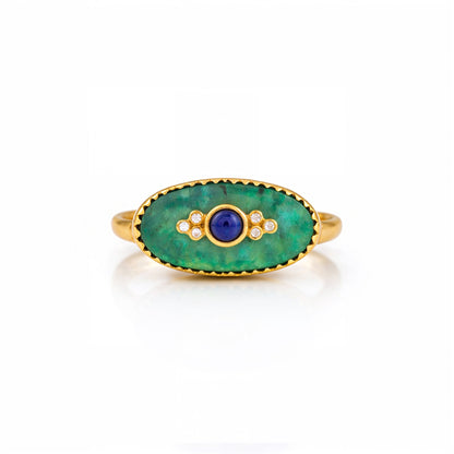 Gold ring with green stone and blue center on a white background