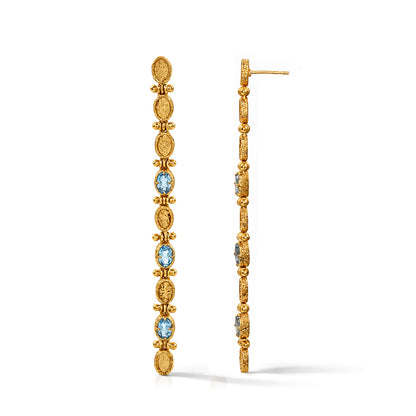 Gold hoop earrings with blue gemstones on a white background