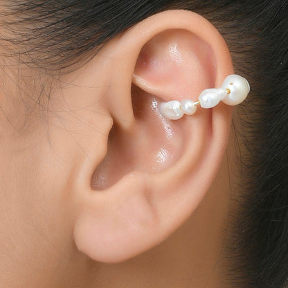 A person wearing an ear cuff featuring a baroque pearl design By Arvino