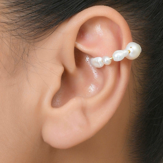 A person wearing an ear cuff featuring a baroque pearl design By Arvino