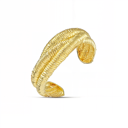 A gold-colored braided cuff bracelet against a white background 