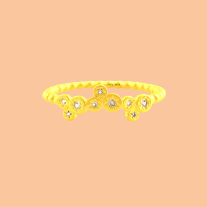 Minimal gold-toned stacking ring featuring star-engraved discs with clear stones, shown on a solid peach backdrop