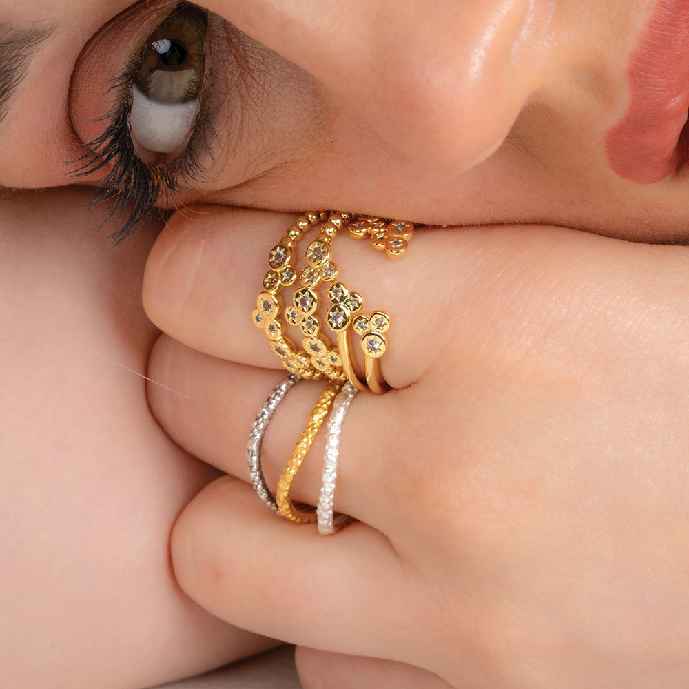 A person wearing multiple rings, with the main focus on a gold ring adorned with sparkling crystals, resembling a constellation.