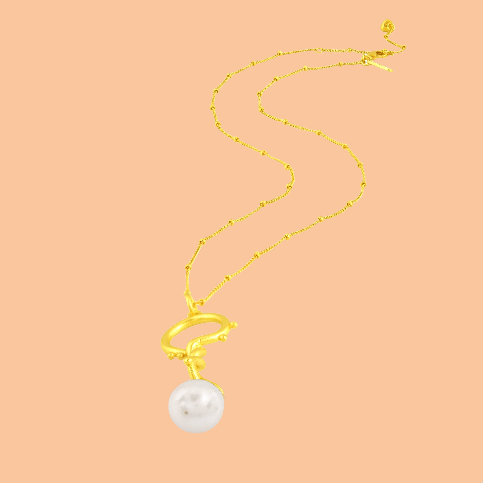 Dewy Pearl Twist Necklace by Arvino on a peack color background. 22 kt gold plated Necklace by arvino