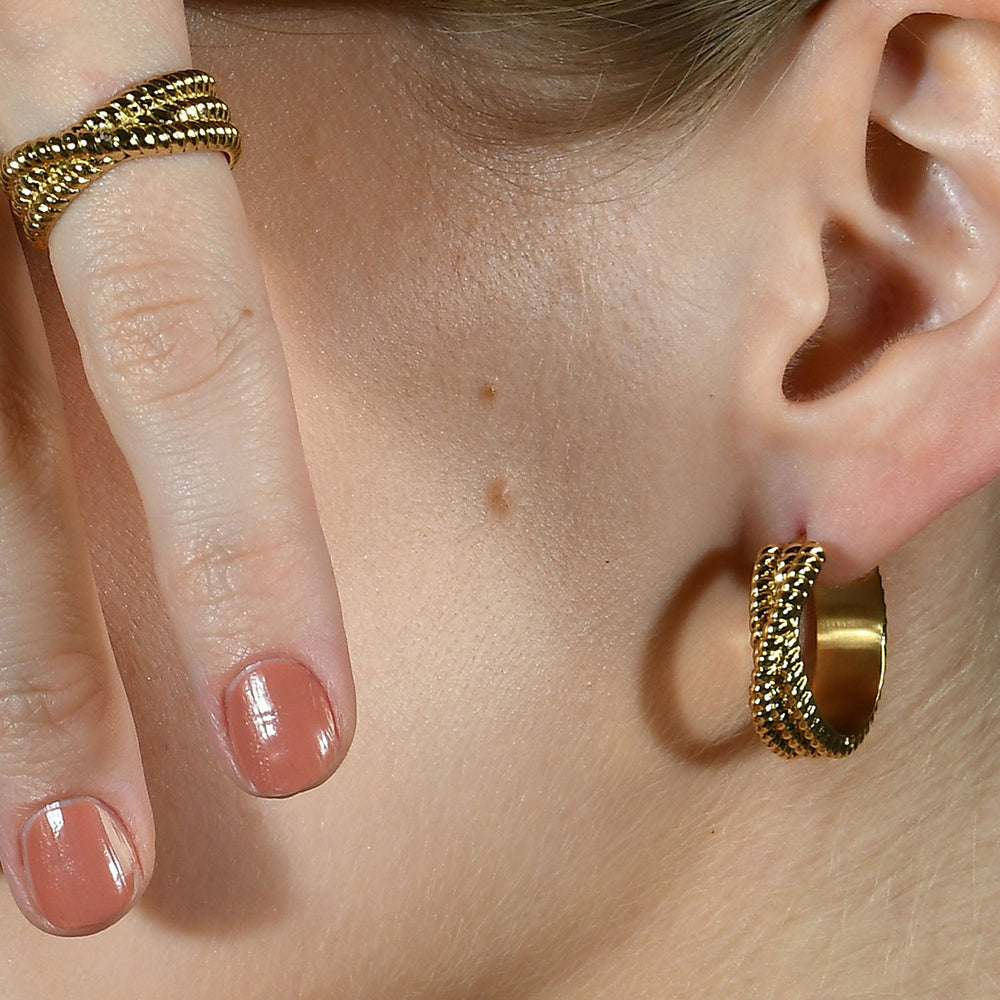 Close up image of a person wearing a intertwined Rope like design earrings by arvino.