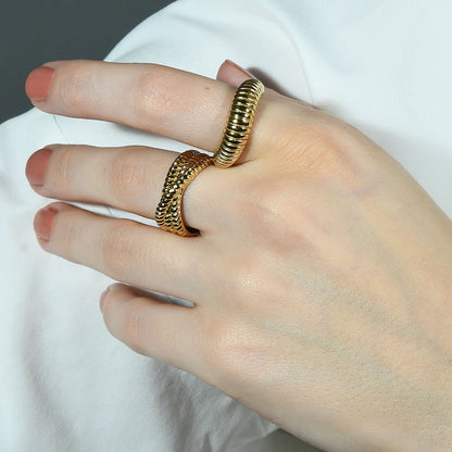 Close up image of a person stacking Intertwined Rope Ring  with a spiral like design ring by arvino.