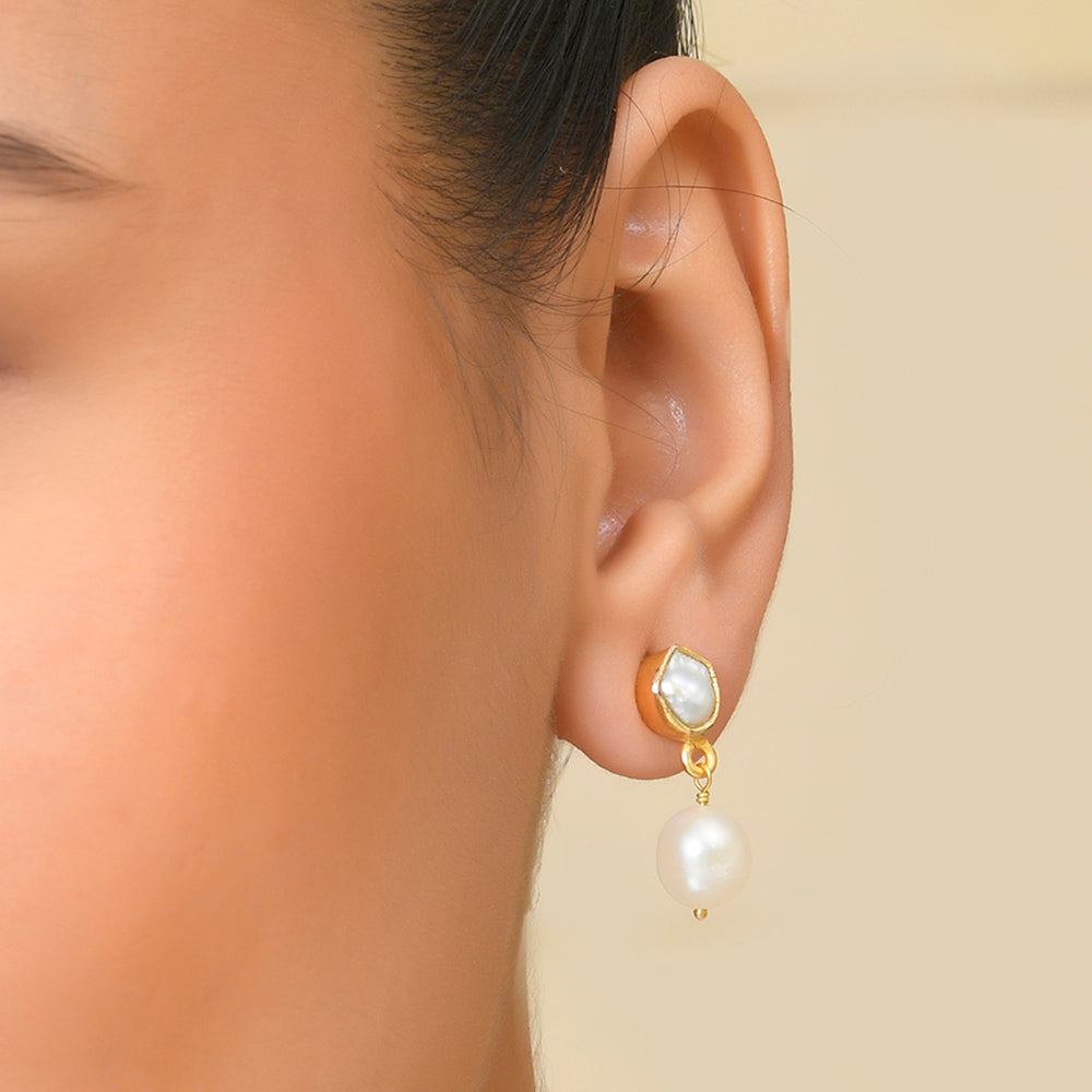 A close-up image of a woman's ear wearing a silver drop earring with a pearl By Arvino