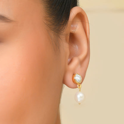 A close-up image of a woman's ear wearing a silver drop earring with a pearl By Arvino