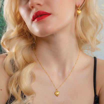 A woman wearing a gold-Plated pendant necklace with a heart-shaped pendant By Arvino