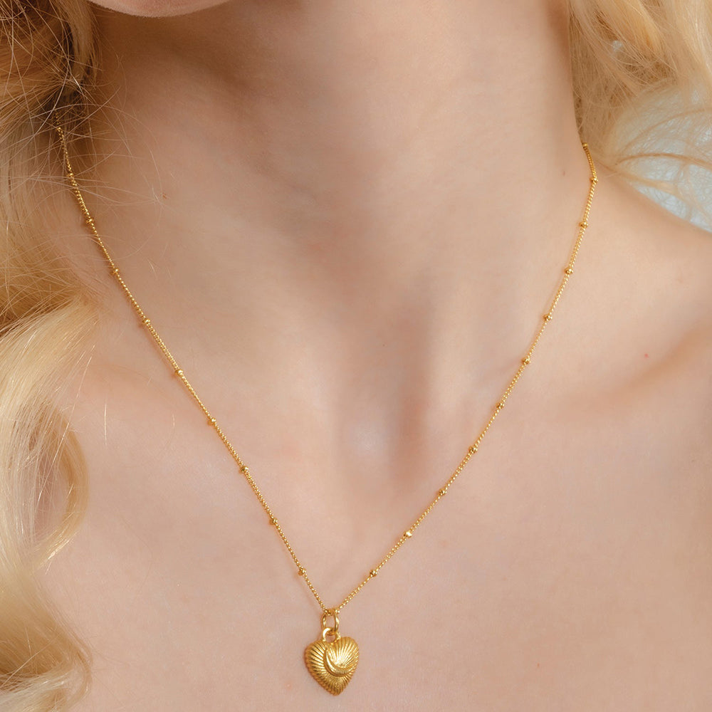 A gold-Plated pendant necklace with a crescent moon and heart design Pendant ,displayed on a person with long blonde hair.