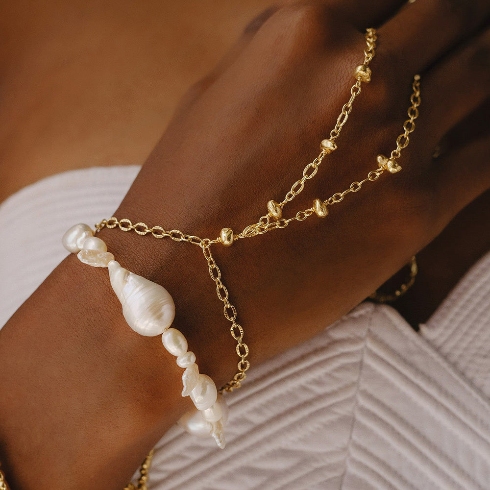 Model image of a person stacking a pearl droplet bracelet with a chain bracelet in hand by arvino.