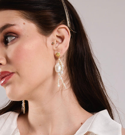 Woman wearing pearl weave earrings by Arvion against a neutral background