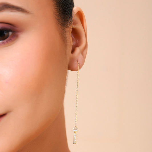 A person wearing a sterling silver threader earring with a zircon-studded bar.