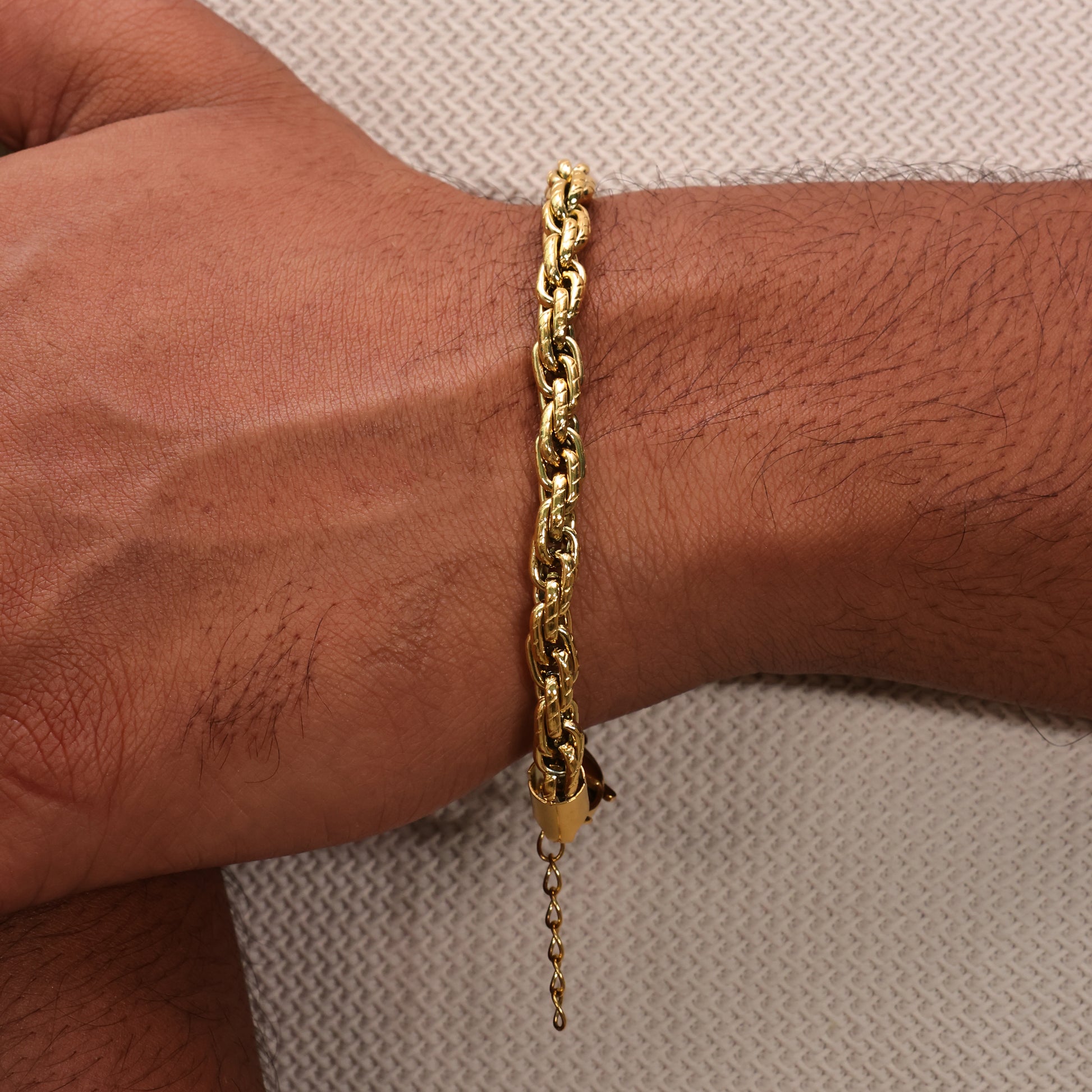Gold plated chain bracelet on a wrist with a neutral white background. Rugged flow men's bracelet by arvino's demi fine jewellery collection