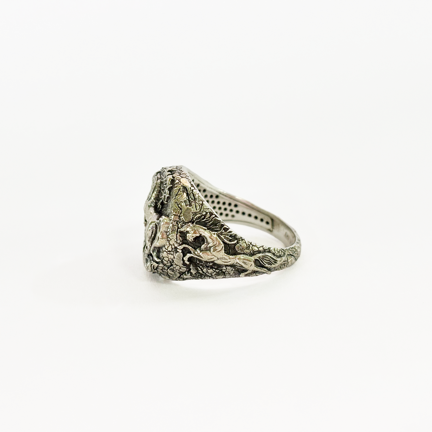 Silver ring with intricate design on a white background