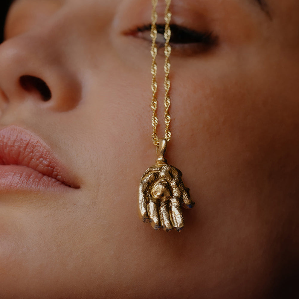 A close-up image of a person wearing a  Sculpted Hand Charm Pendant By arvino
