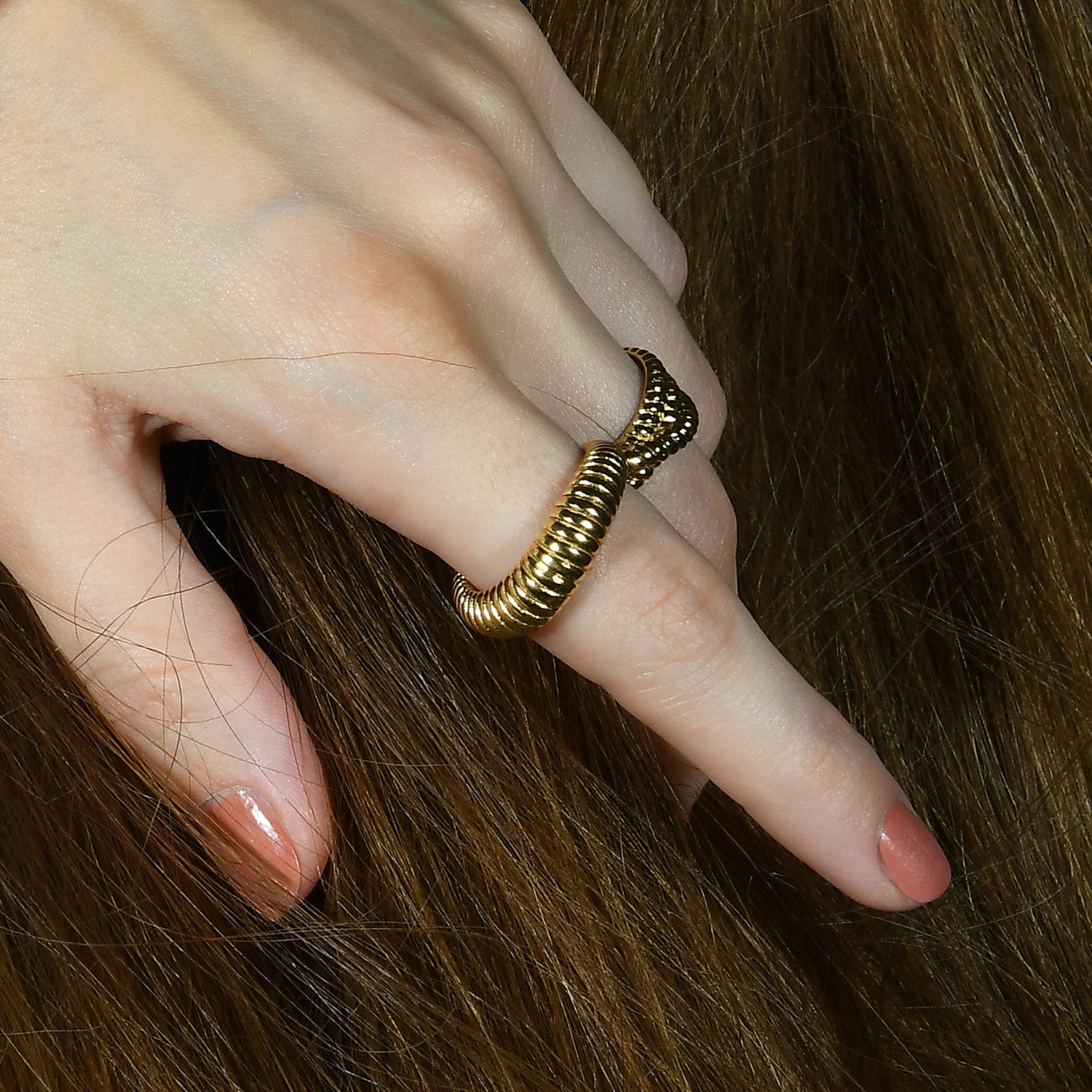 A person's hand displaying a gold-plated sculpted ridge ring on their finger.