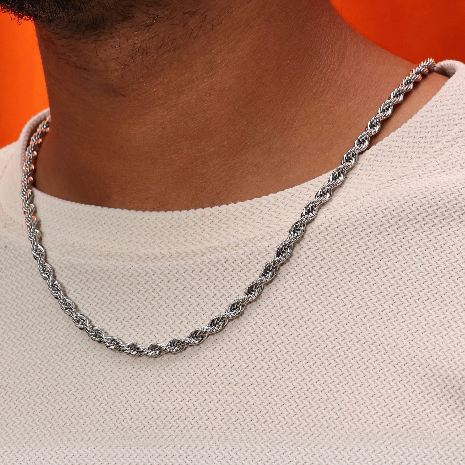 Silver plated Forged rope neckchain shot on model against a orange background.