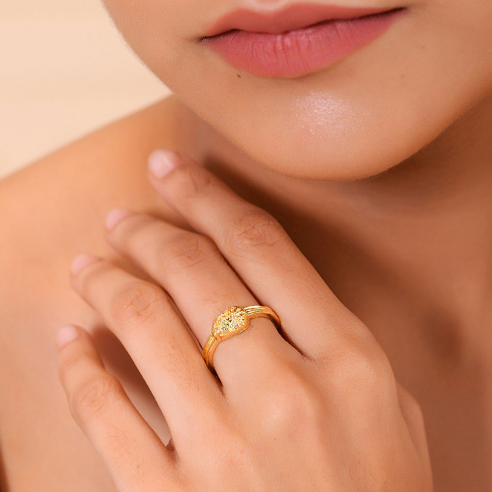 A person wearing a gold-colored ring with a textured surface on their finger.