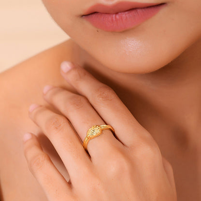 A person wearing a gold-colored ring with a textured surface on their finger.